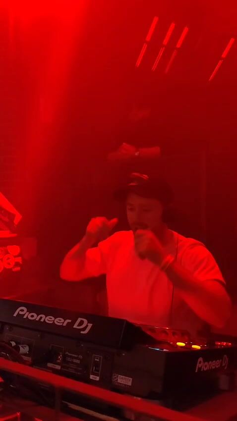 Theon Bower behind Pioneer decks in red light
